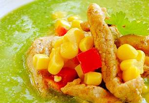 Grønn suppe med topping av svinekjøtt, paprika og mais