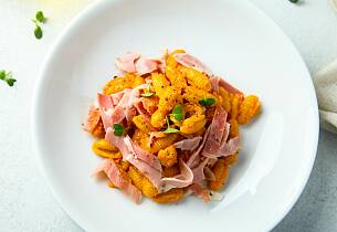 Pasta med røykt skinke og et glass rød pesto gir feriestemning