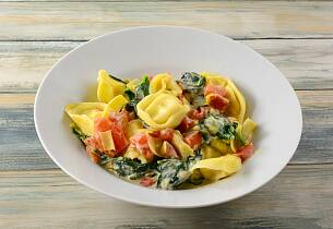 Tortellini ai Formaggio med parmaskinke og spinat i en kremet tomatsaus